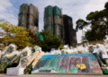 A painting depicting a photograph taken by Reuters photographer Tyrone Siu sits at a makeshift flower memorial nearby to the Wang Fuk Court housing complex residents after the deadly fire, in Tai Po, Hong Kong, China [Reuters]