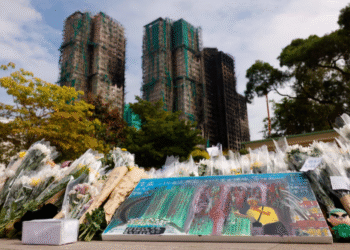 A painting depicting a photograph taken by Reuters photographer Tyrone Siu sits at a makeshift flower memorial nearby to the Wang Fuk Court housing complex residents after the deadly fire, in Tai Po, Hong Kong, China [Reuters]