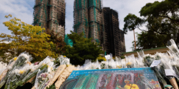 A painting depicting a photograph taken by Reuters photographer Tyrone Siu sits at a makeshift flower memorial nearby to the Wang Fuk Court housing complex residents after the deadly fire, in Tai Po, Hong Kong, China [Reuters]