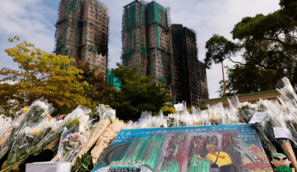 A painting depicting a photograph taken by Reuters photographer Tyrone Siu sits at a makeshift flower memorial nearby to the Wang Fuk Court housing complex residents after the deadly fire, in Tai Po, Hong Kong, China [Reuters]