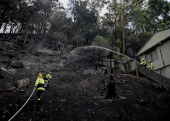 Firefighters work at the site where bushfire destroyed homes along Glenrock Parade, in Koolewong on the Central Coast of New South Wales, Australia