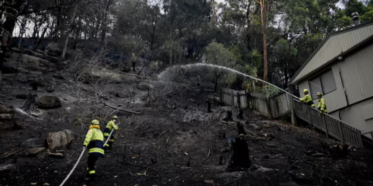 Firefighters work at the site where bushfire destroyed homes along Glenrock Parade, in Koolewong on the Central Coast of New South Wales, Australia